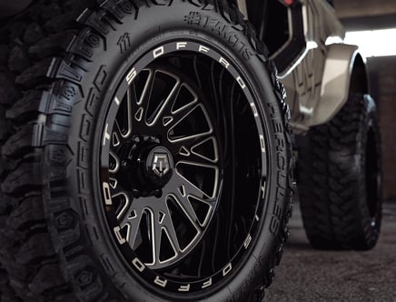 Close-up of an off-road tire with a detailed black alloy wheel.