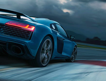 Blue sports car driving on a racetrack, with motion blur and illuminated taillights.