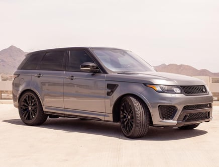 Gray luxury SUV parked on a rooftop with mountains in the background.