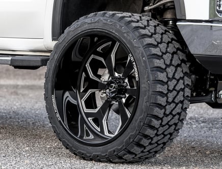 Close-up of a vehicle's large black alloy wheel with a rugged off-road tire.