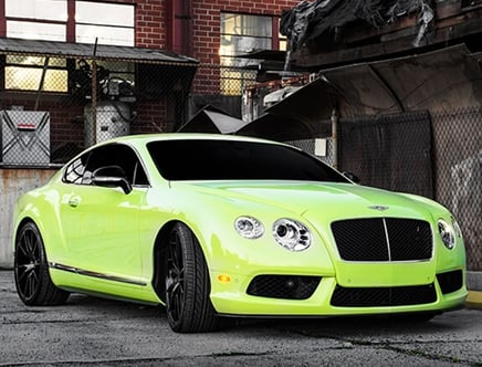 A lime green luxury sports car parked in an industrial area.