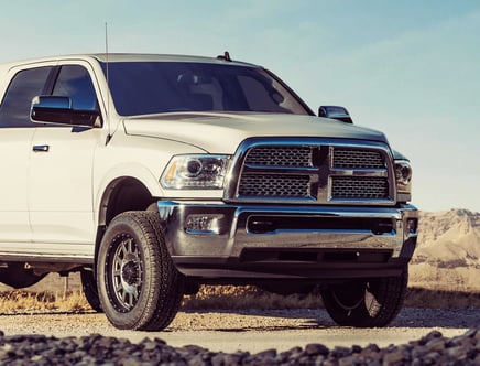 White pickup truck with chrome accents parked on a gravel road in a mountainous area.