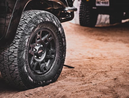 Close-up of an off-road vehicle's tire on sandy terrain.