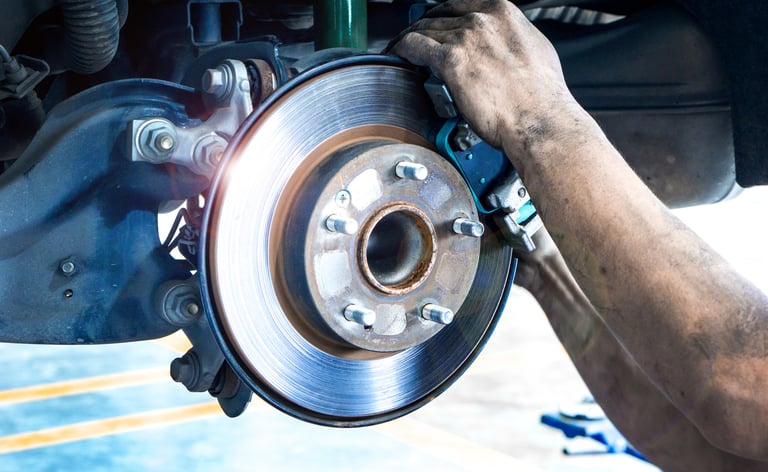 Mechanic working on a car's brake disc.