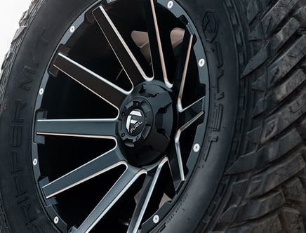 Close-up of a black alloy wheel with a multi-spoke design on an off-road tire.