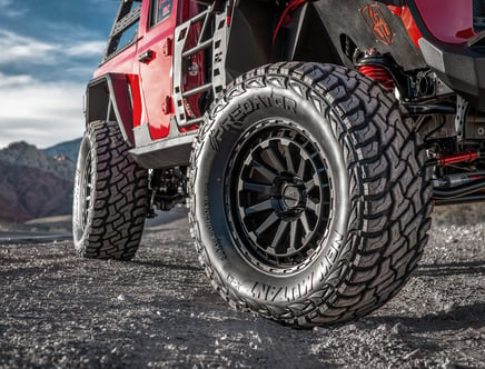 Close-up of a lifted off-road vehicle with large tires on a rugged landscape.