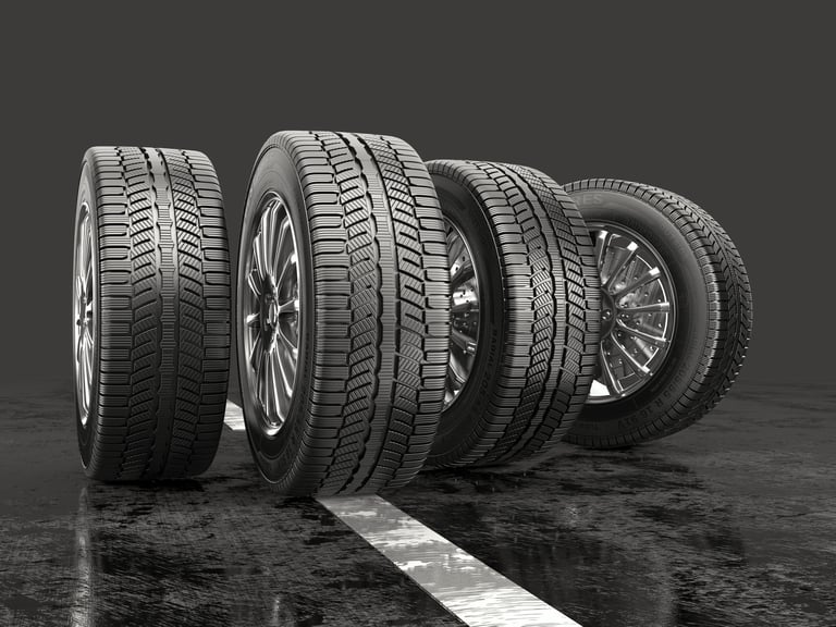 Four car tires with different tread patterns lined up on a wet surface.