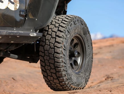 Close-up of an off-road vehicle tire on rocky terrain.