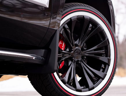 Close-up of a black vehicle wheel with red and white accents on the tire.