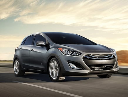 A silver hatchback car driving on a road with a blurred background.