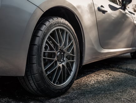 Close-up of a car's front wheel with dark alloy rims on a silver vehicle.