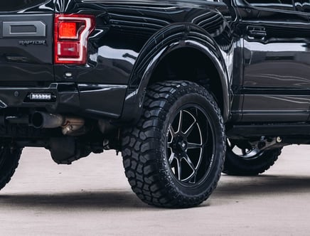 Close-up of the rear section of a black truck with large off-road tires.