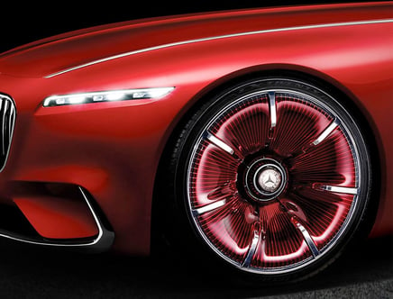 Red luxury car front with illuminated headlight and futuristic wheel design.