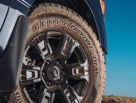 Close-up of a truck wheel with a Geolandar A/T tire and a Nissan logo on the rim.