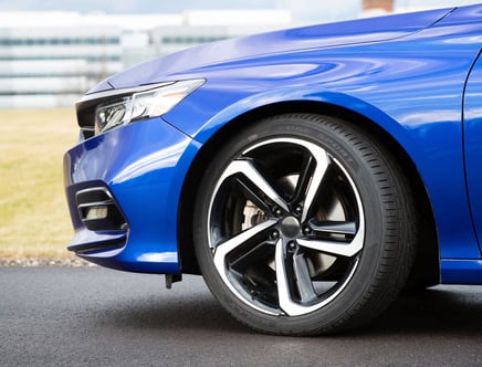 Close-up of a blue car's front fender and wheel with modern alloy rims.