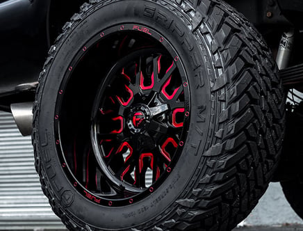 Custom black and red off-road tire with rugged tread pattern.