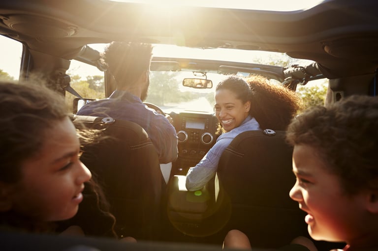 Family enjoying a car ride with open roof during a sunny day.