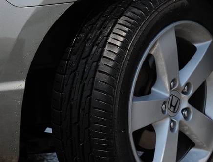 Close-up of a car wheel with a visible tire and Honda logo on the rim.