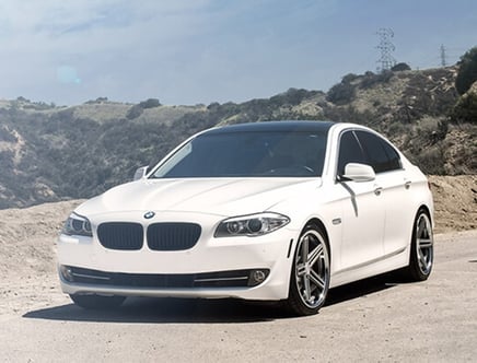 White BMW sedan parked on a mountainous road.