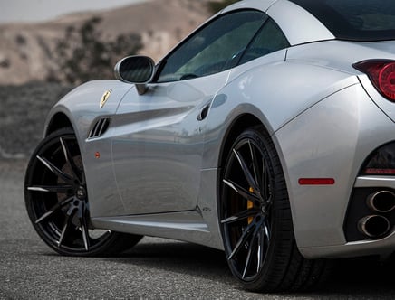 Silver sports car with black rims and dual exhaust.